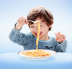 Ein Kind isst Spaghetti mit Tomatensoße mit einer Gabel