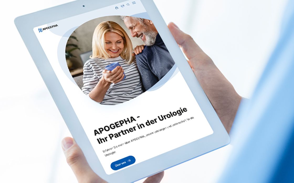 Ein Tablet in der Hand zeigt die Website von APOGEPHA mit einem Bild eines lächelnden älteren Paares. Der Text lautet: „APOGEPHA – Ihr Partner in der Urologie“.