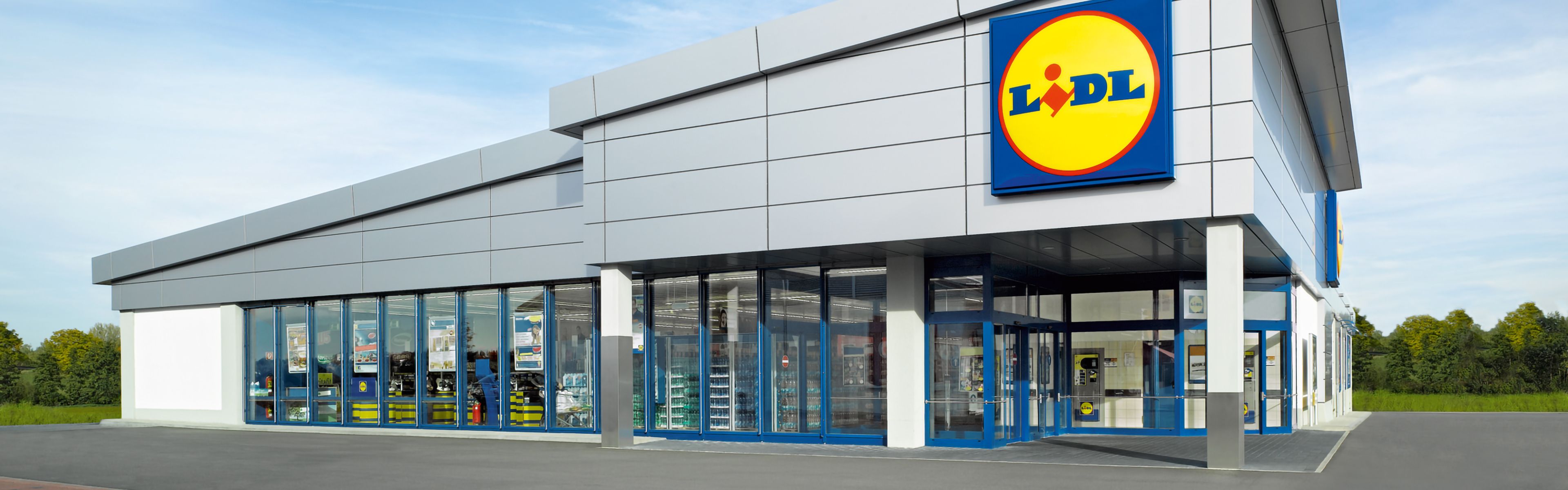 AuĂenansicht eines modernen Lidl-Supermarkts mit glĂ€sernem Eingangsbereich und dem deutlich sichtbaren Logo des GeschĂ€fts auf dem GebĂ€ude.