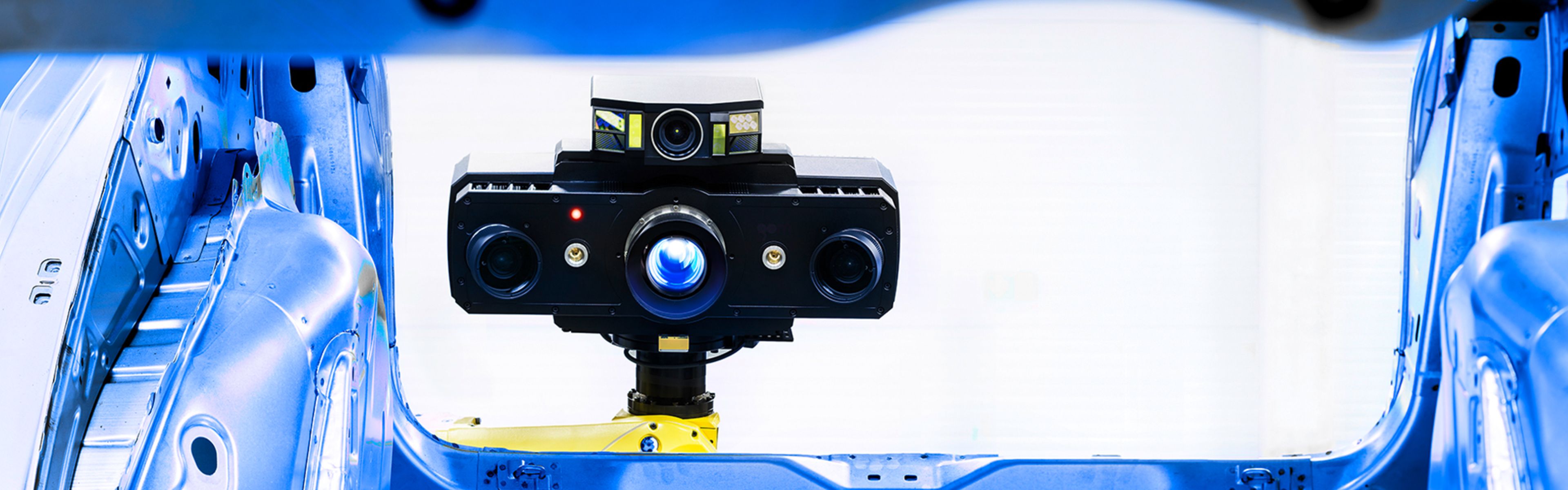 Ein Hightech-Kamerasystem, montiert auf einem gelben Stativ innerhalb eines blauen Industriegestells, mit mehreren nach vorn gerichteten Objektiven.